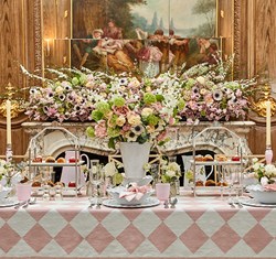 Table set up with pink flowers and tablecloth.