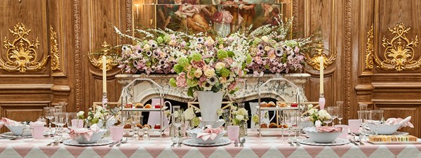 Table set up with pink flowers and tablecloth.