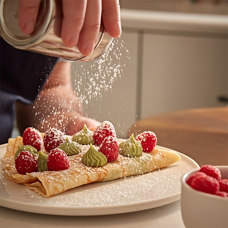 A sweet crepe with pistachio whipped cream and raspberries