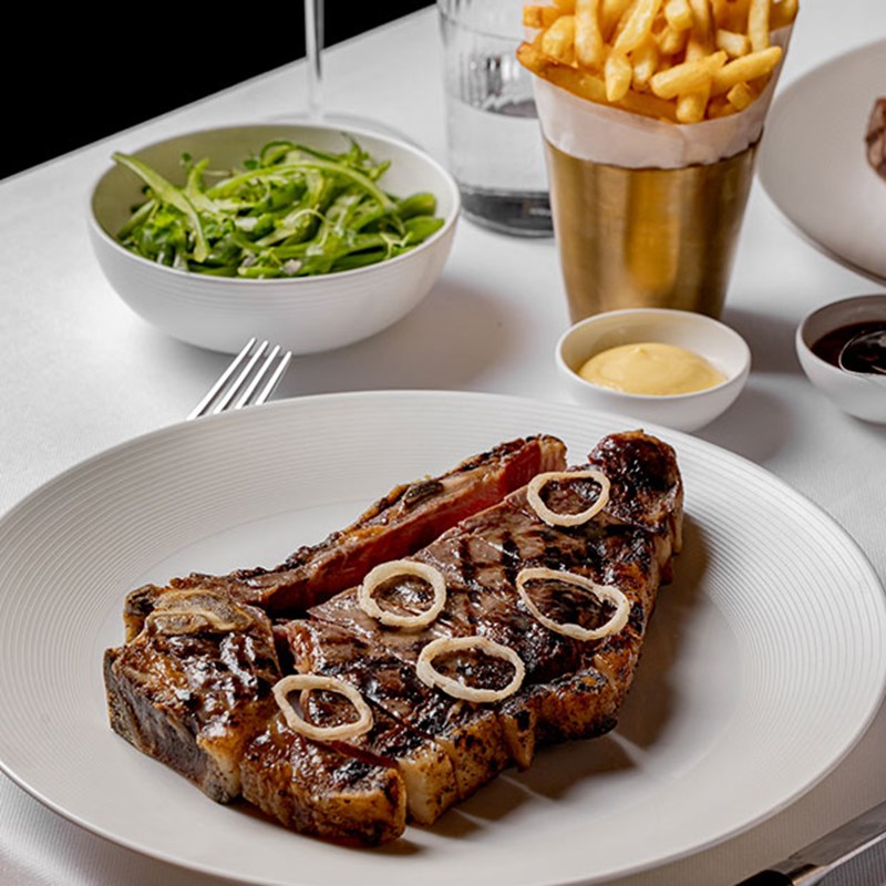 Thick cut of meat on plate with chips in background
