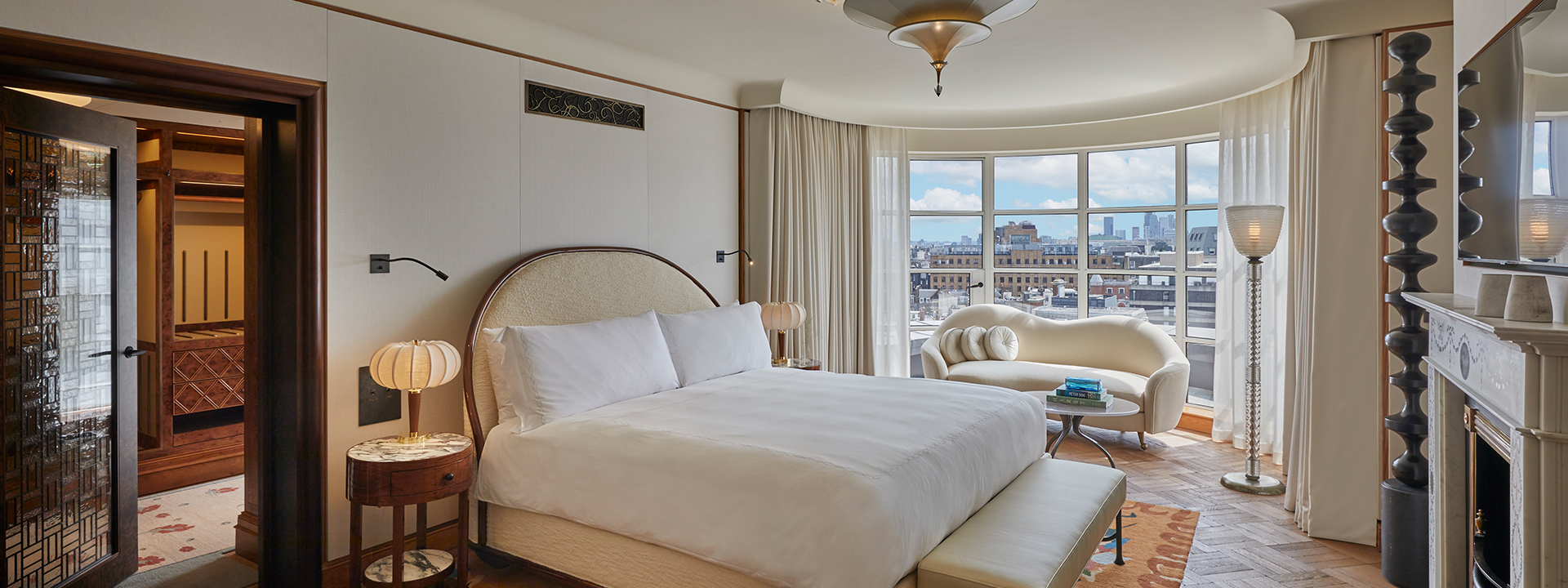 Mews Pavilion bedroom with bed, sofa and a view on the roofs of London from the window.