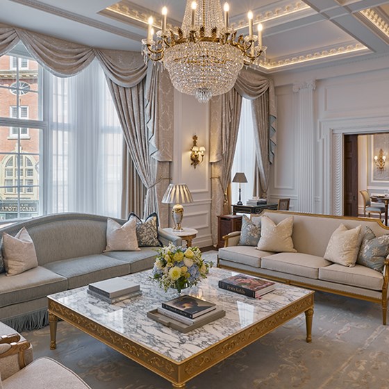 The living room of the Georgian Suite with sofas and a beautiful marble table. There is a grand chandelier on the ceiling. In the background is the dining room.