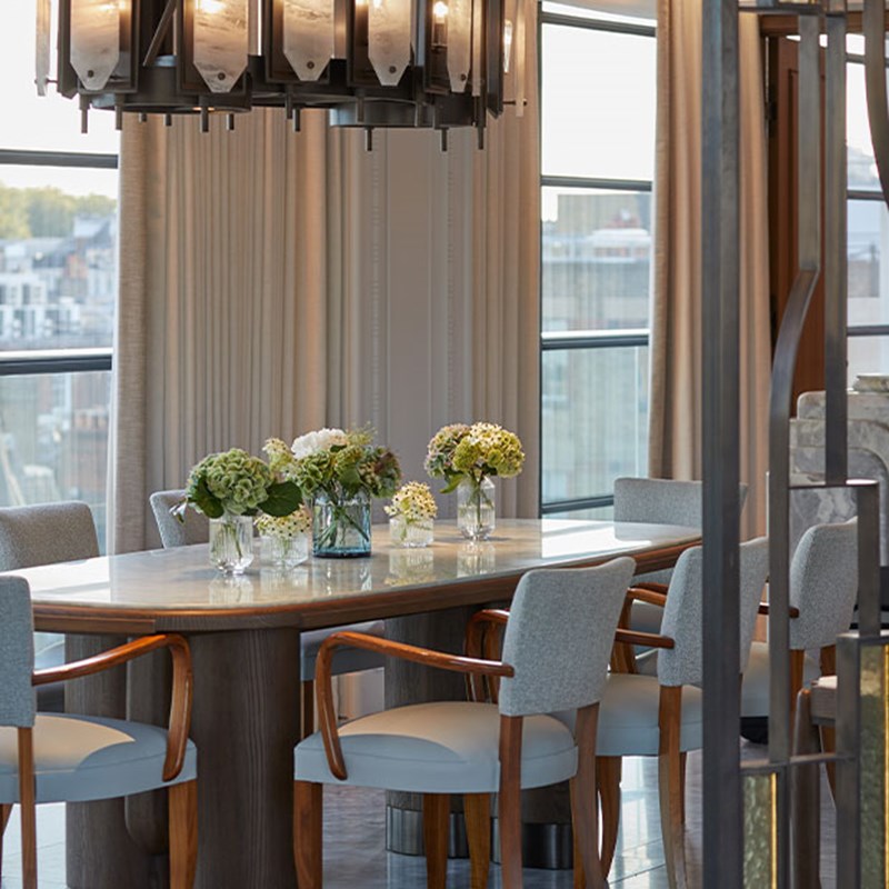 Grey dining chairs around marble table with hanging modern light
