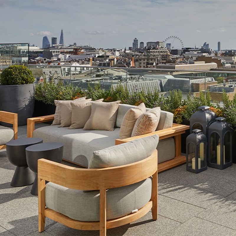 Grey lounge chair outside on terrace with London skyline in the background