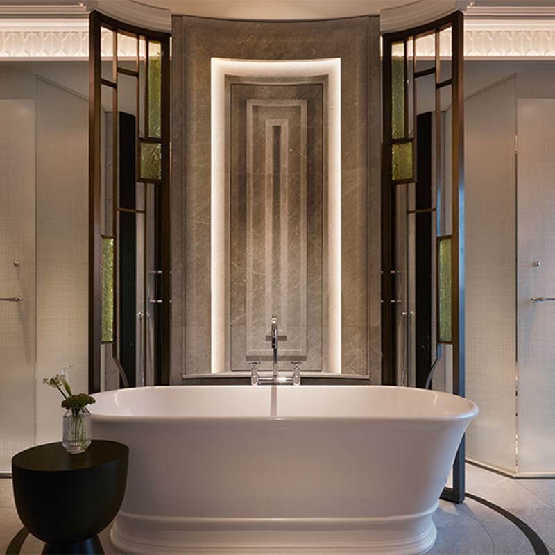 Dimly lit marble bathroom with free-standing bathtub