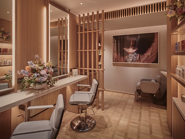 Josh Wood salon at Claridge's Spa - chairs for hair cutting on the left hand-side with large wide mirrors on the wall, and washing hair area in the background.